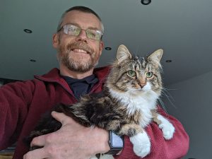 Simeon holding a tabby and white long haired cat
